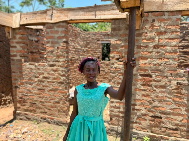 In 2025, we met Violet again in Uganda. Today, she is standing in front of her own house, which she is currently building.